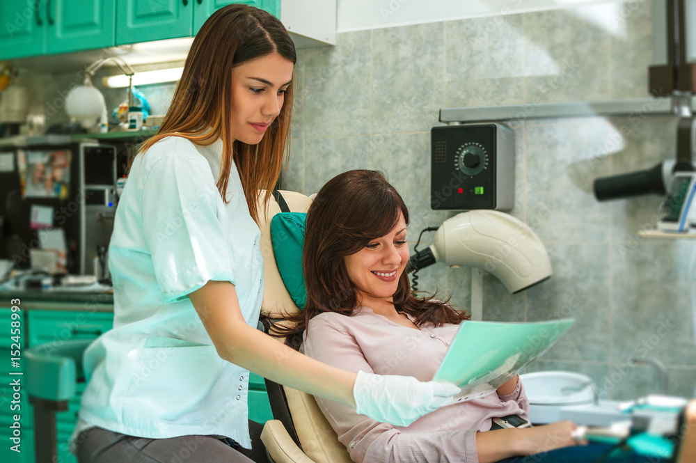 Dentist examining patients teeth X-Ray image in dental office.