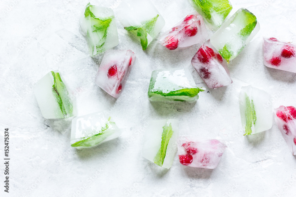 mint and red berries in ice cubes stone background top view