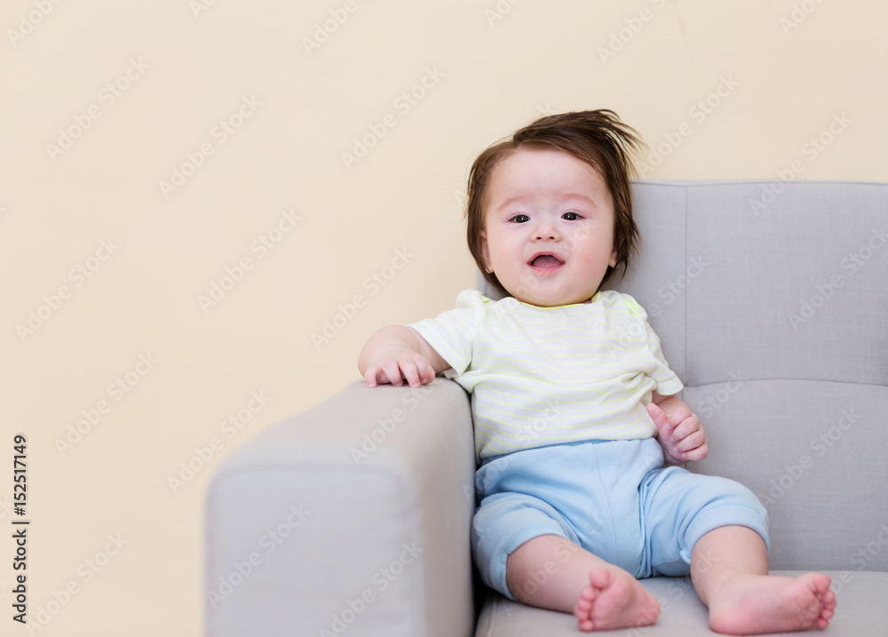 Happy baby boy sitting on a sofa