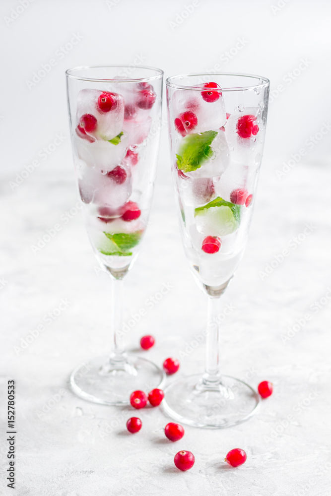 mint and red berries in ice cubes in glasses white background