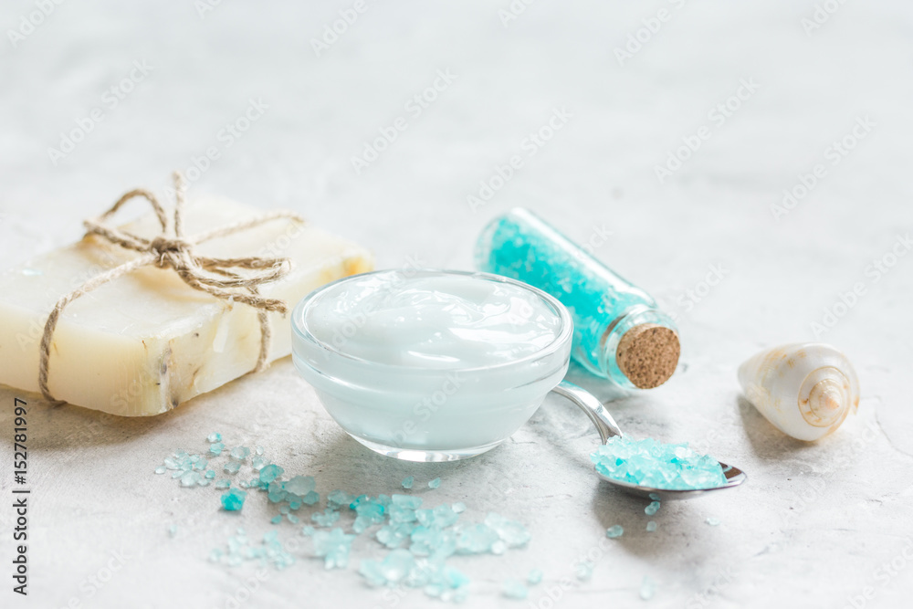 Home cosmetic with cream and blue sea salt on stone background