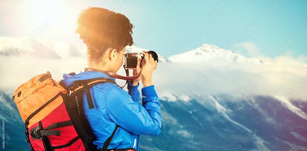 Composite image of hiker with backpack taking picture