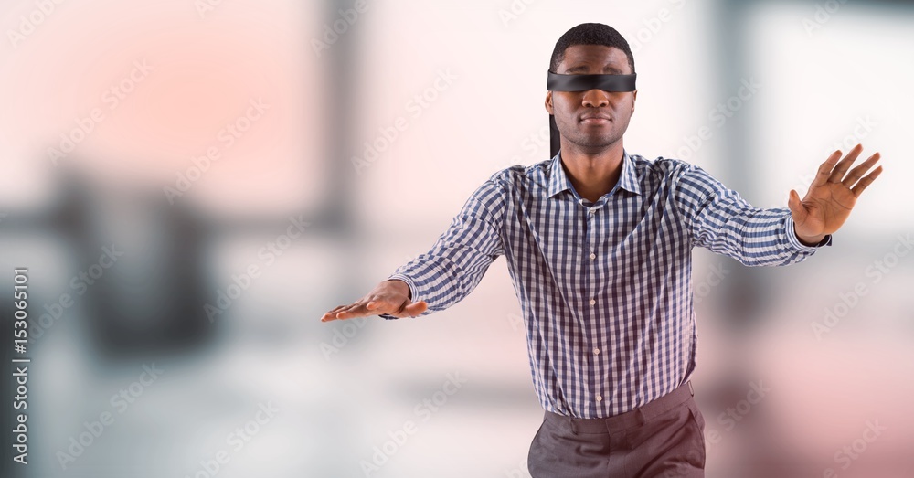 Business man blindfolded against blurry grey office 