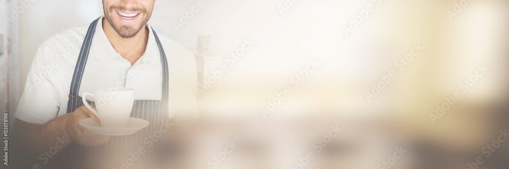 Smiling male barista holding cup of coffee at cafe