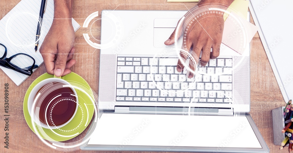 Businessman using laptop while holding coffee cup