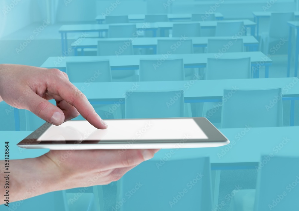 Hand touching a tablet in a blue classroom