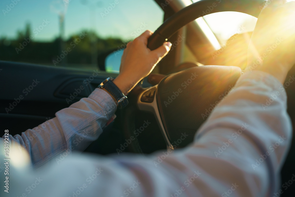 Woman is driving a car at sunset