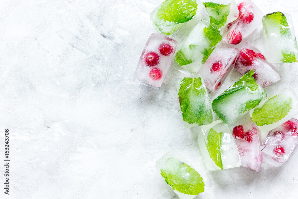 frozen red berries in ice cubes on stone background space for text top view