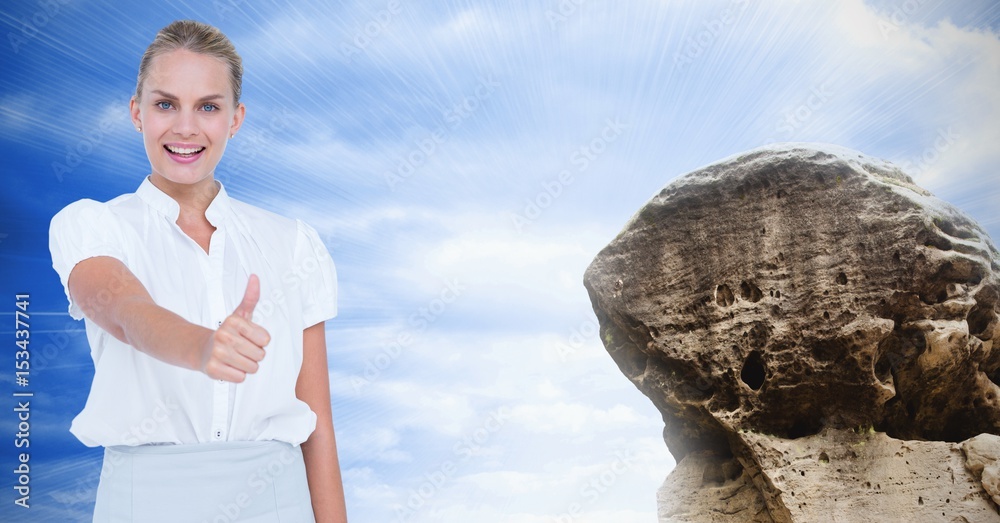 Businesswoman showing thumbs up sign by rock