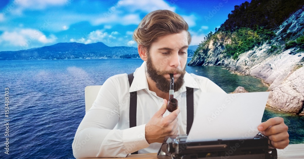 Hipster smoking pipe while using typewriter against lake