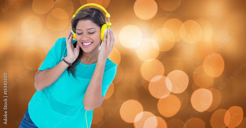 Smiling woman listening to music on headphones against bokeh