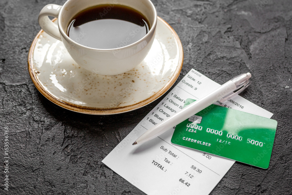 coffee and receipt bill for payment by credit card on dark table background