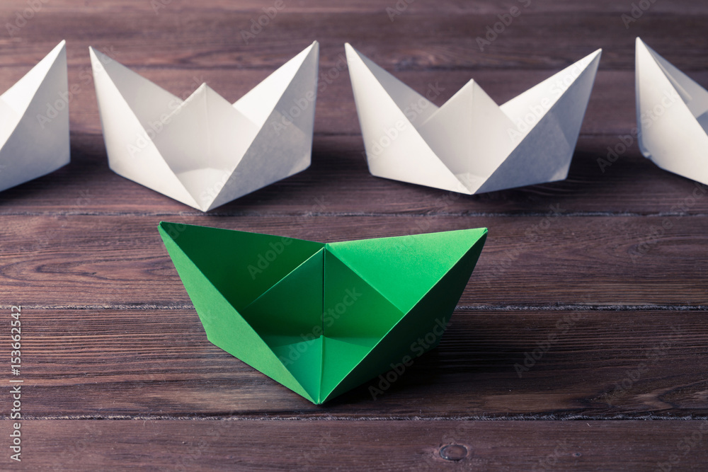 Business leadership concept with white and color paper boats on 