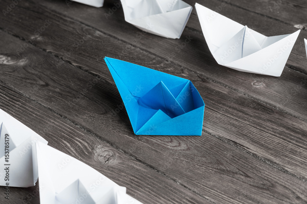 Business leadership concept with white and color paper boats on 