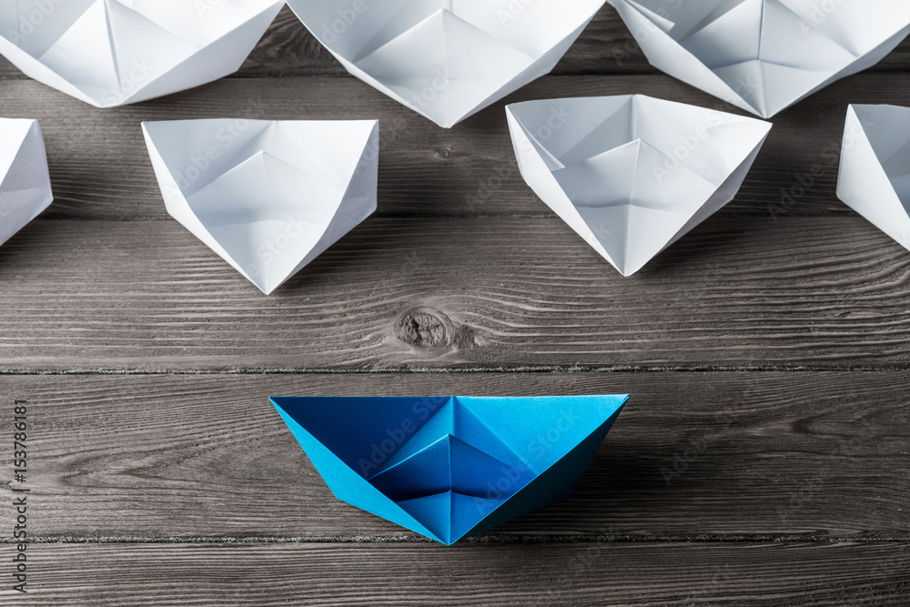 Business leadership concept with white and color paper boats on 