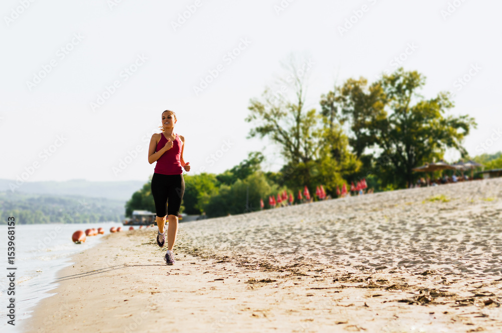 Running woman. Female runner jogging during outdoor workout on beach.