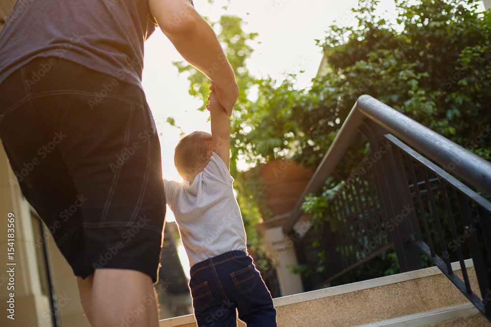 Asian boy and father walking together on the stair carefully