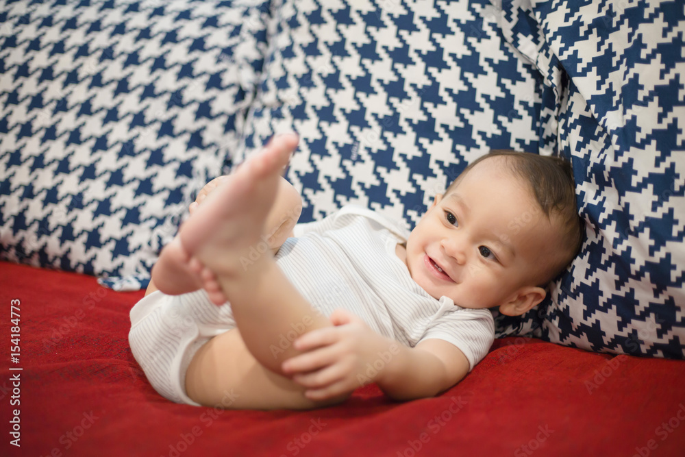 Happy little Asian boy lying on the bed