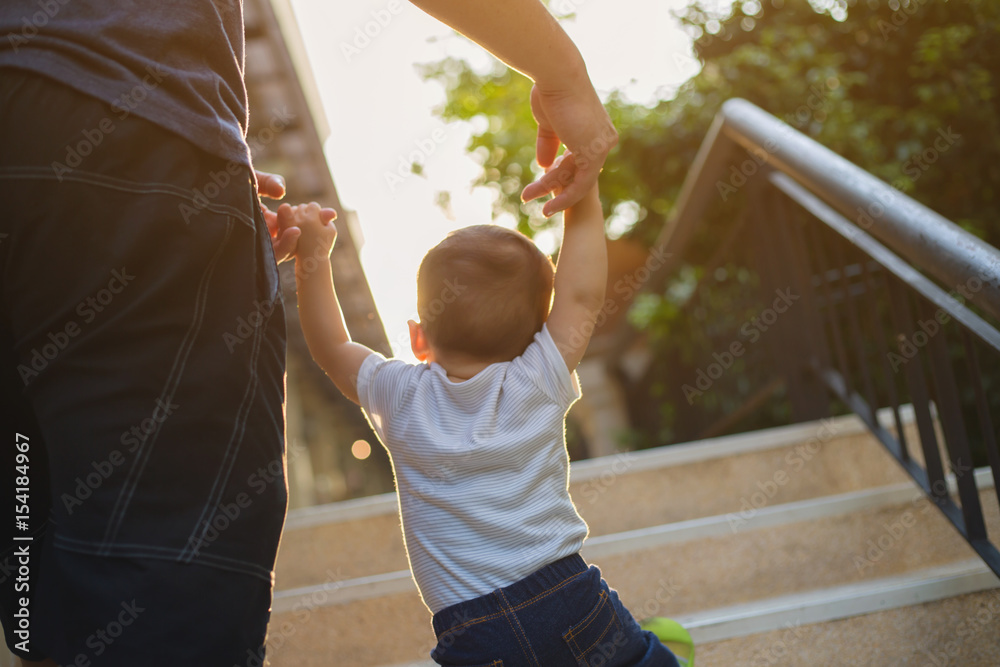 Asian boy and father walking together on the stair carefully