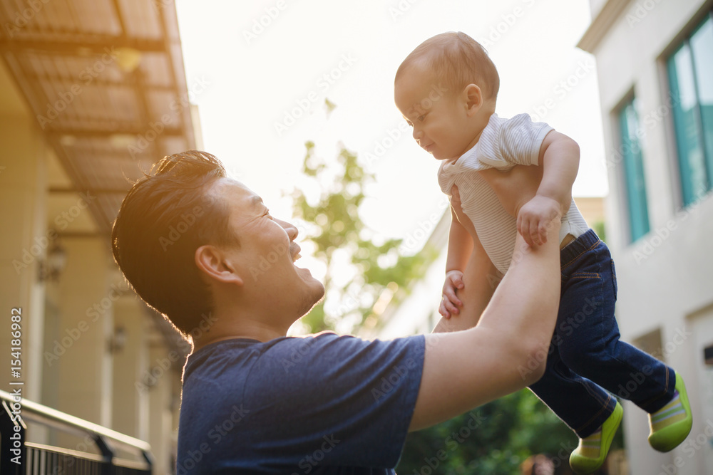 Happy Asian man holding his son to the air