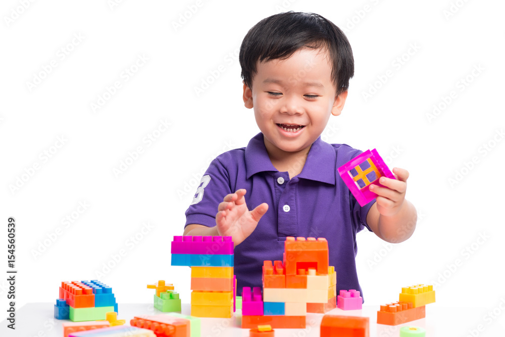 Kid boy playing with blocks from toy constructor isolated