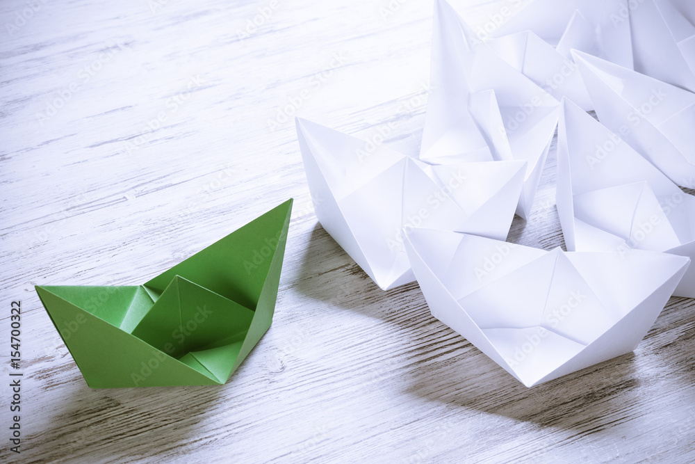 Business leadership concept with white and color paper boats on 