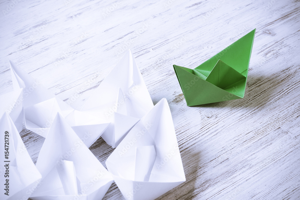 Business leadership concept with white and color paper boats on 