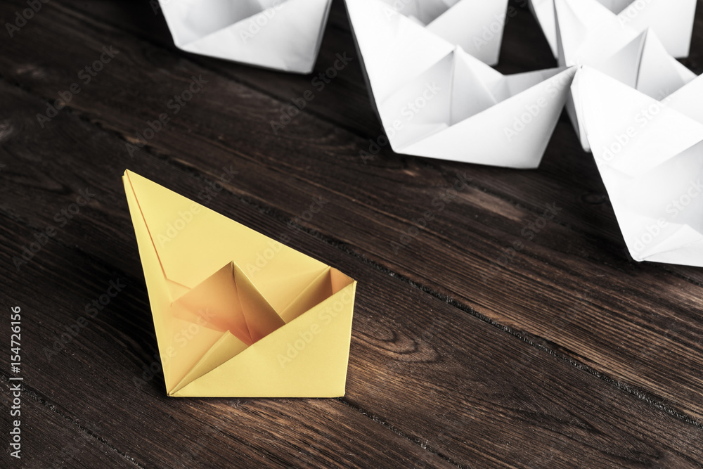 Business leadership concept with white and color paper boats on 