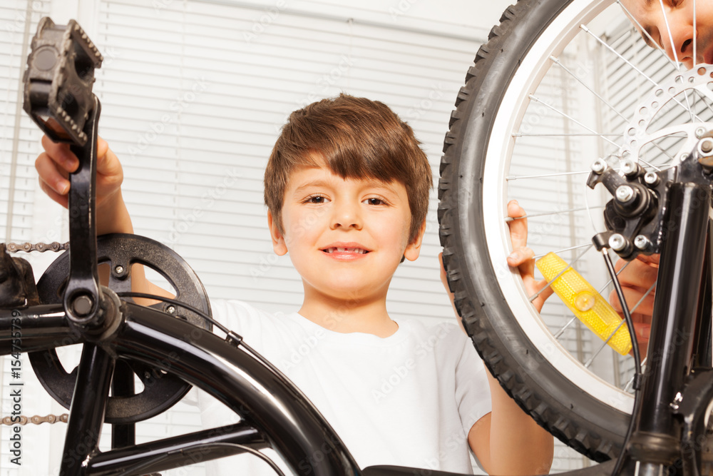 Smiling six years old boy repairing his bicycle