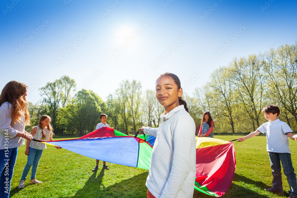 Young African girl playing parachute with friends