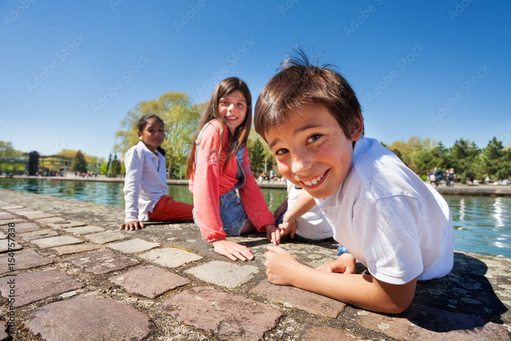 Cute boy sitting on the embankment with friends