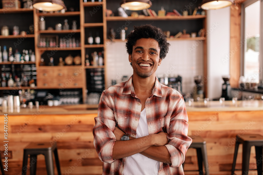 Handsome young man with his arms crossed in a cafe