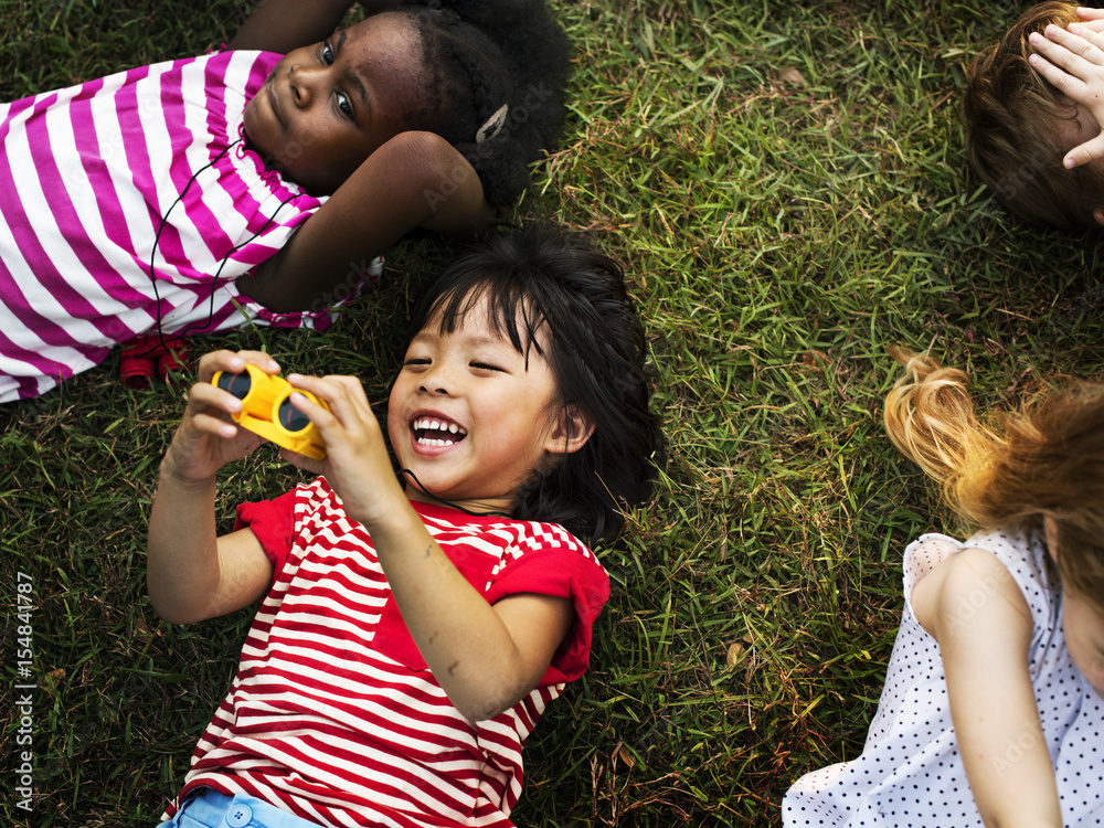 Group of kindergarten kids lying on the grass at park and relax with smiling