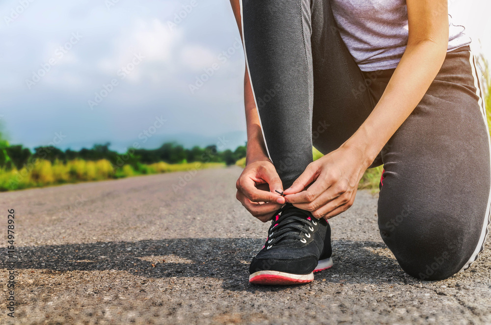 Female runner tied shoe at the park.