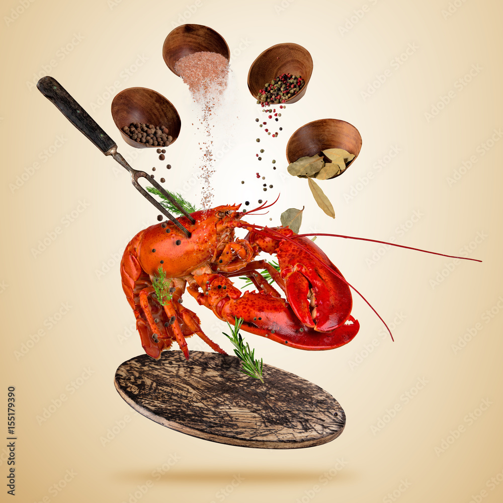 Fresh American lobster with falling spices, flying above wooden board