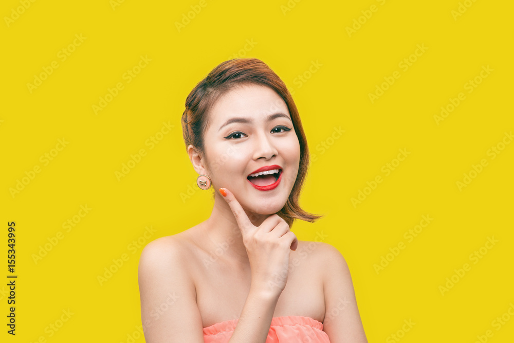 Glamorous asian fashion model posing in vivid colourful clothes and glasses over yellow background.