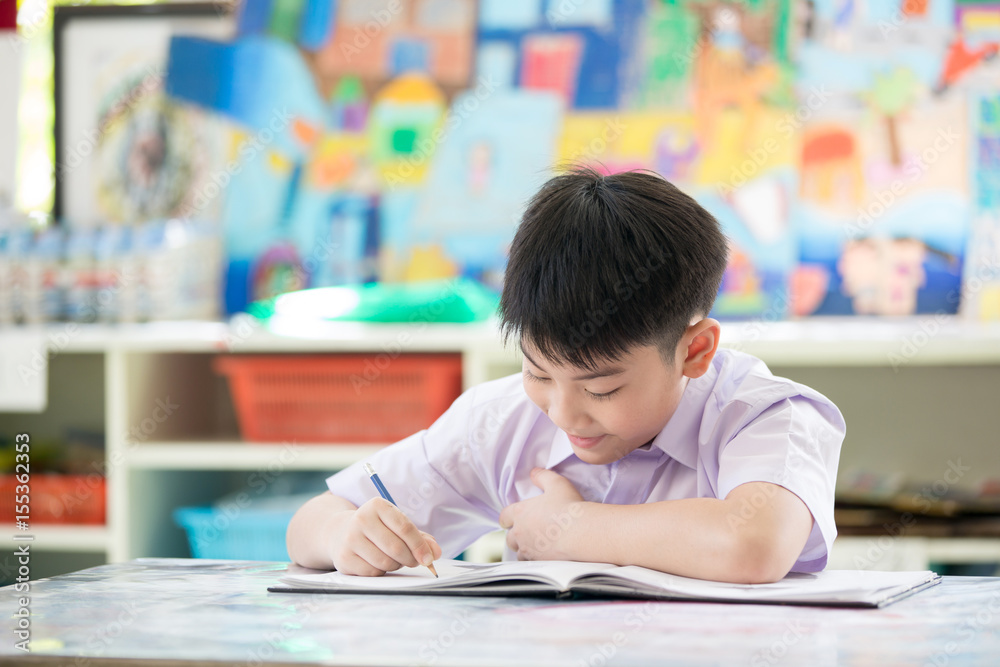 Happy asian child writing book with smile face.