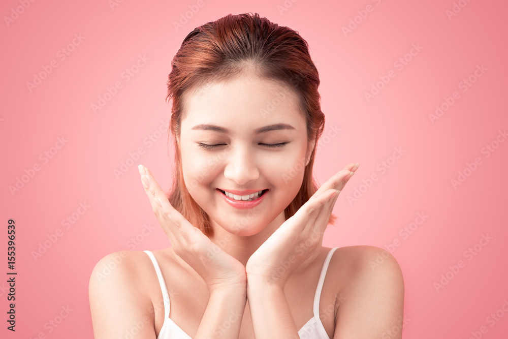 Portrait of Beautiful Skin care woman enjoy and relax touching her face on pink background