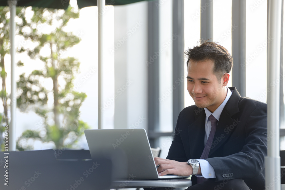 Young Asian businessman  working with laptop computer at outdoor cafe