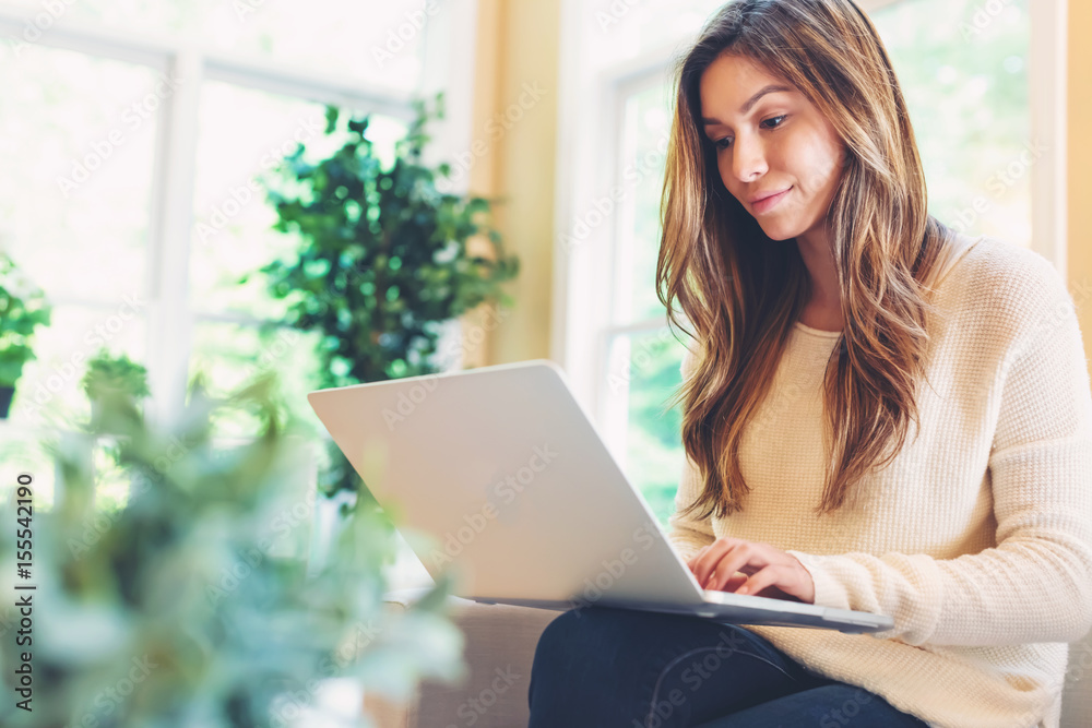 Happy young latina woman using her laptop at home