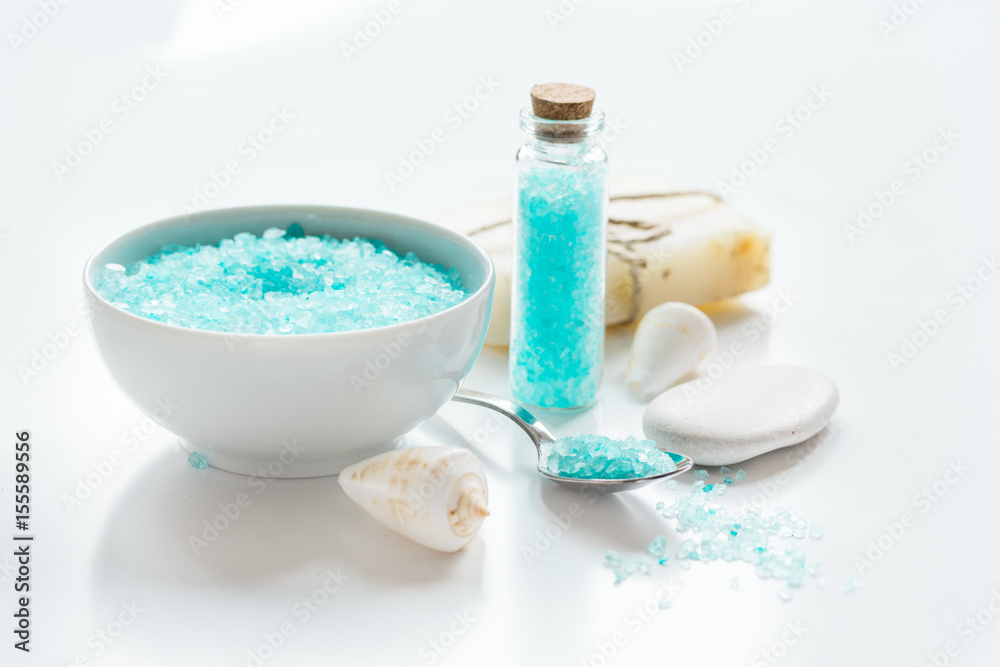 blue bath salt, body cream and shells for spa on white table background