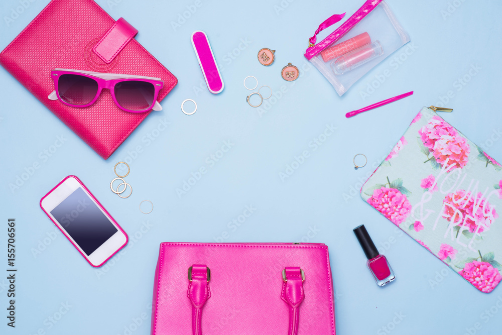 Summer concept. Pink handbag with accessories on light blue background