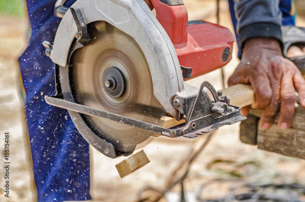 carpenter uses a circular saw to cut wood on the work area