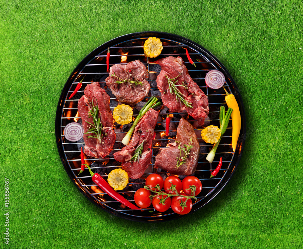 Top view of fresh meat and vegetable on grill placed on grass