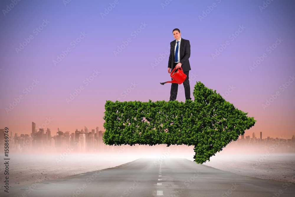 Composite image of businessman holding red watering can