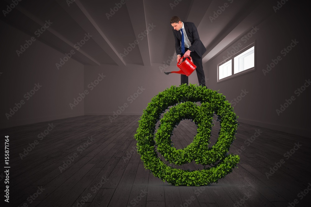 Composite image of businessman holding red watering can