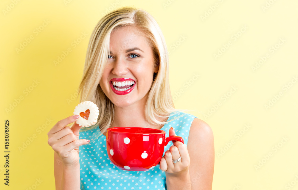 Happy young woman with cookie and coffee