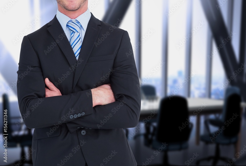 businessman crosses his arms against office background 