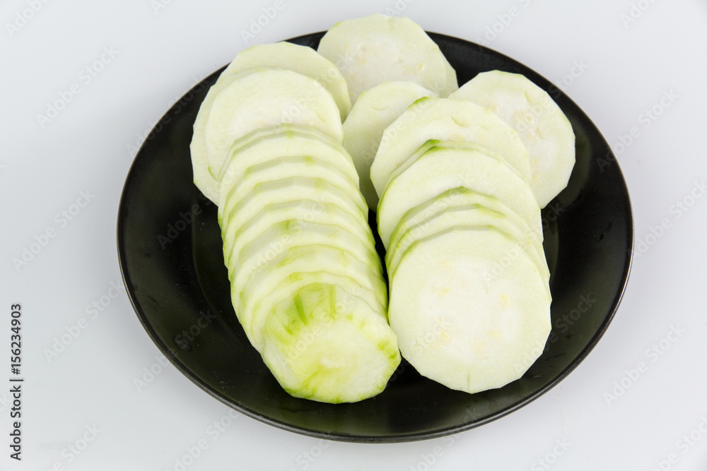 slices of Loofah on a black plate isolated on white background
