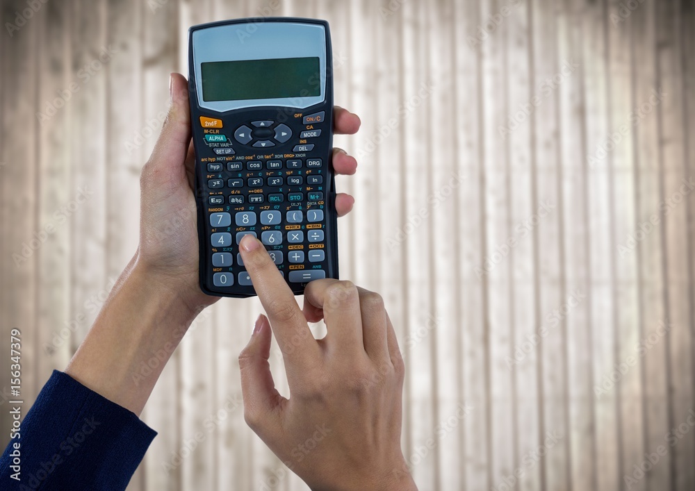 Hands with calculator against blurry wood panel